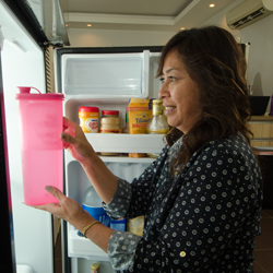 Woman placing items in refrigerator.